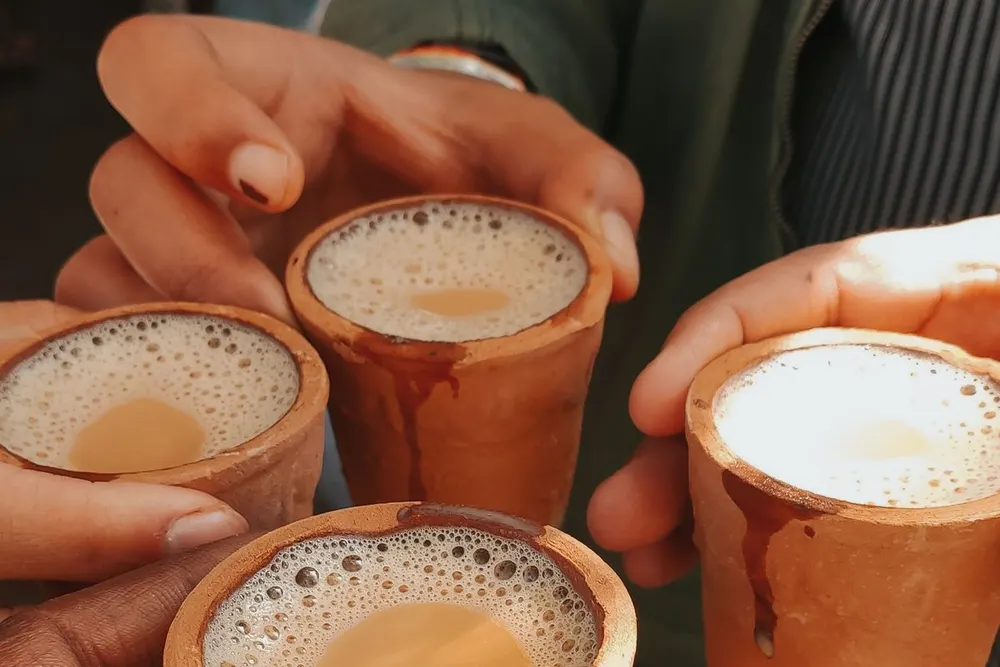 Friends sharing a round of chai in clay cups